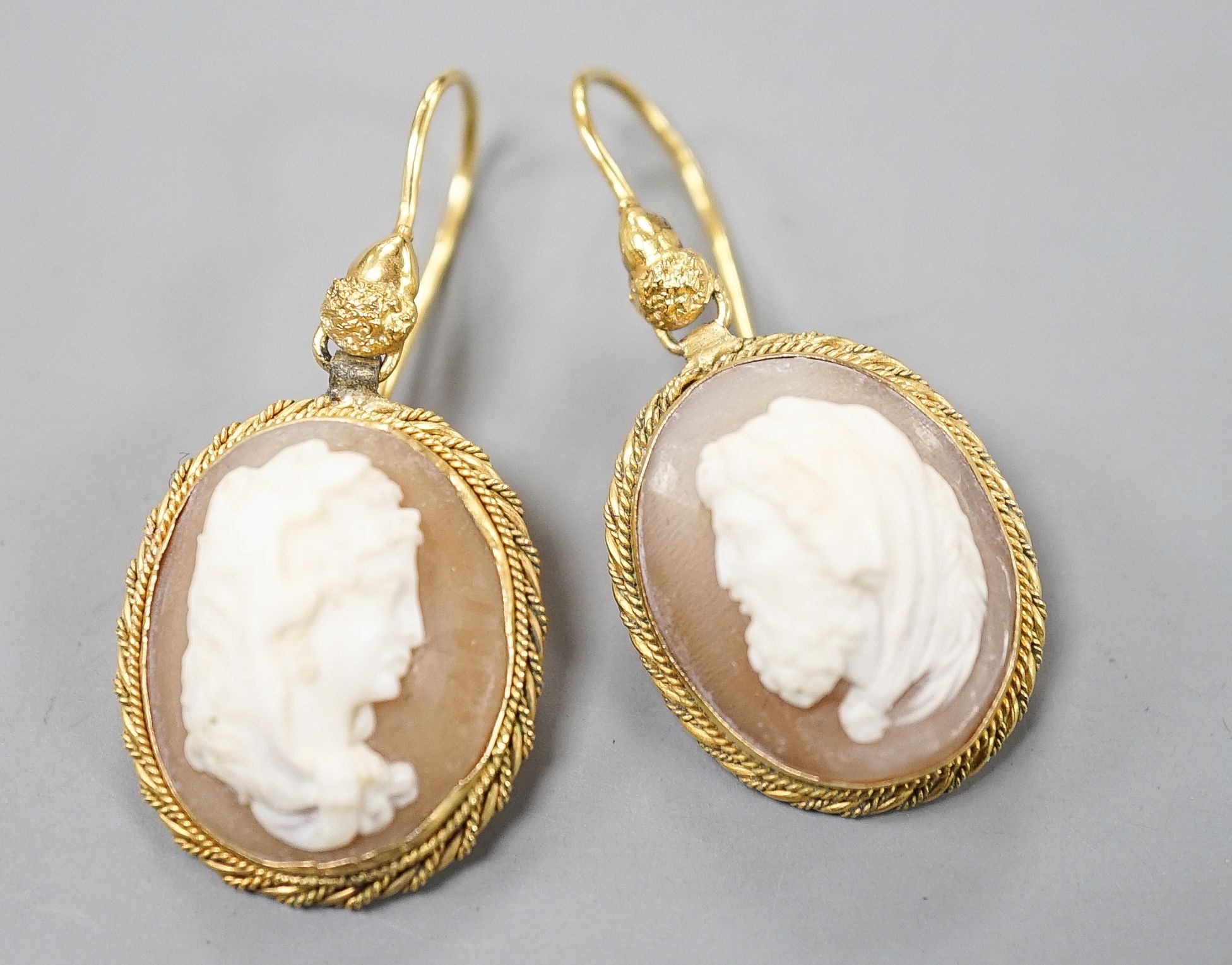 A pair of early 20th century yellow metal and oval cameo shell earrings, carved with a lady to sinister and a gentleman to dexter, overall 40mm, gross 6.2 grams.